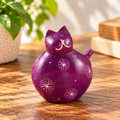 Purple handmade soapstone fat cat with floral patterns displayed on a wooden tabletop